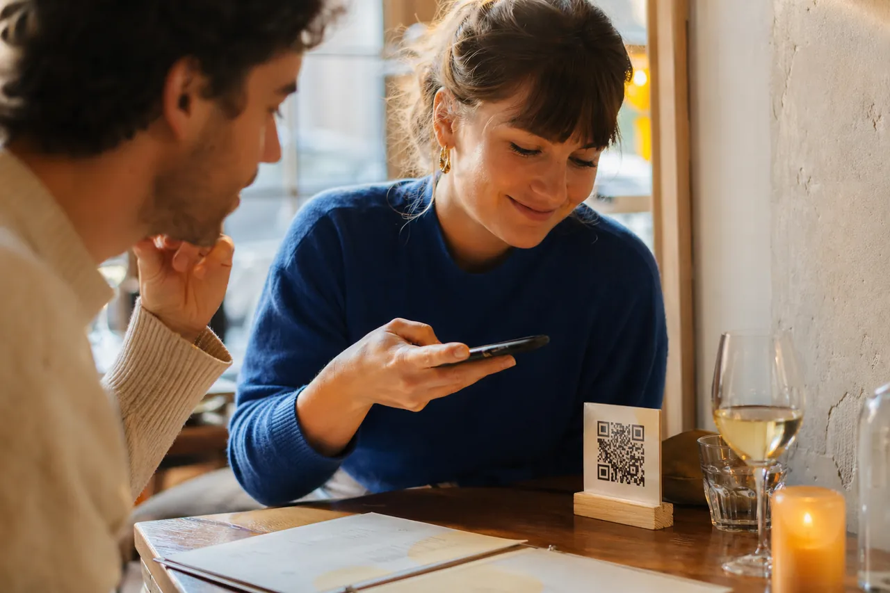 Cliente scannant un chevalet QR code à table pour consulter la carte du restaurant sur son smartphone